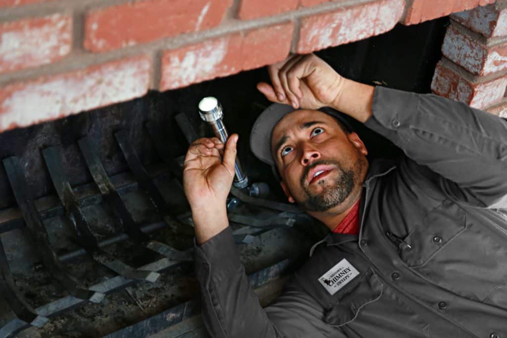 Midtown technician inspecting the inside of a fireplace with a flashlight