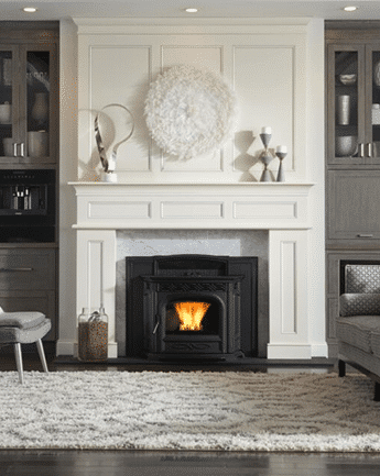 A black wood-burning stove with a visible flame sits inside a white fireplace mantel, flanked by dark built-in cabinets and a shaggy rug in front.