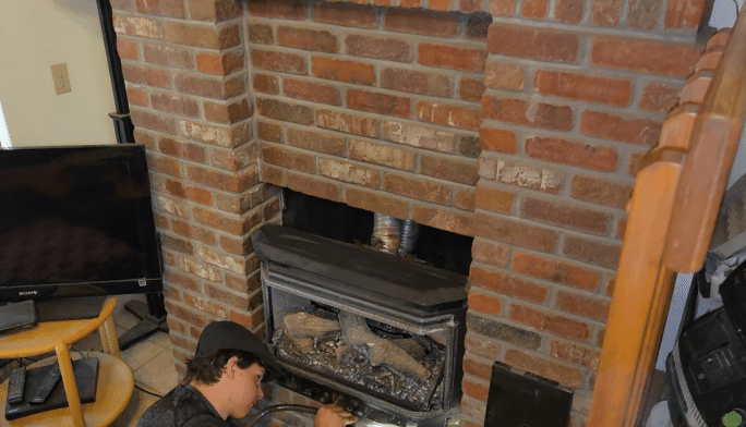 Midtown technician servicing a gas fireplace insert in a brick surround