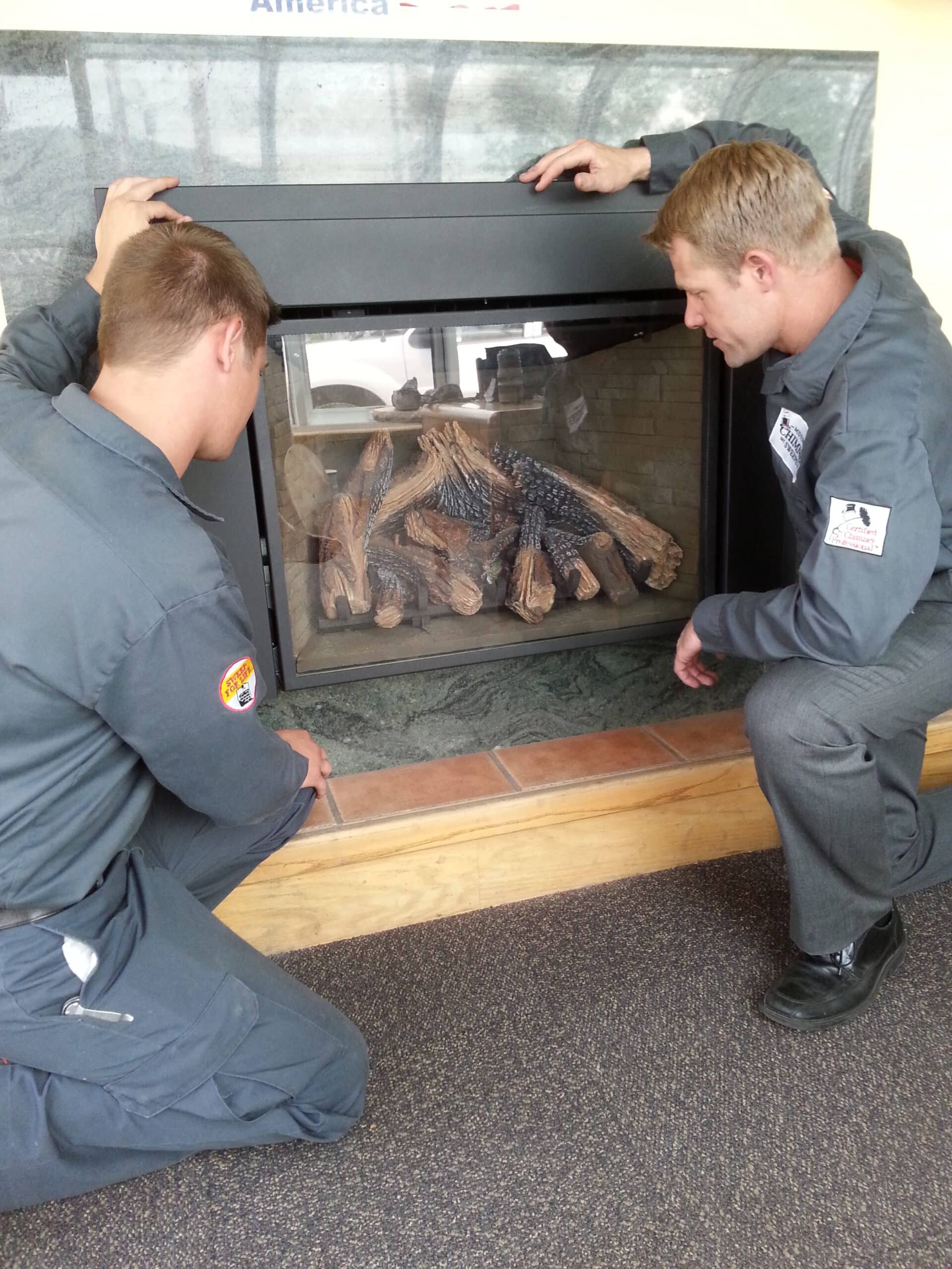 Technicians installing gas logs in a fireplace