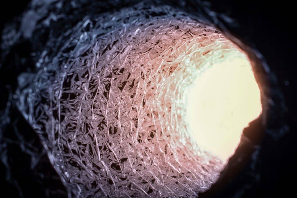 A cylindrical woven tube lined with reflective strands, seen from inside toward a bright opening.